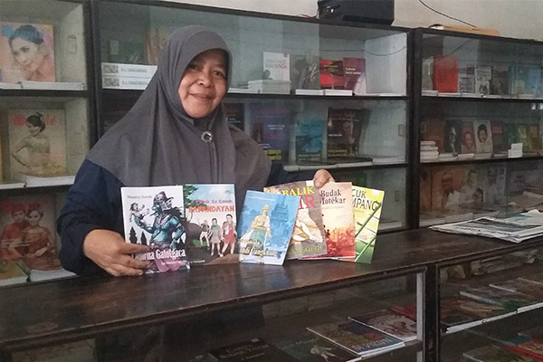 Ibu Asih memperlihatkan koleksi buku di Toko Buku Merpati. (Foto: Opet)